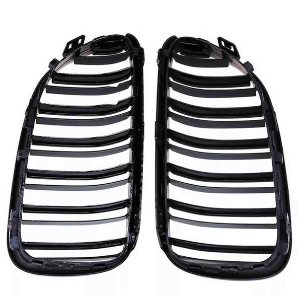 Two black plastic car grille inserts lie side by side, featuring multiple horizontal slats, against a plain white background.