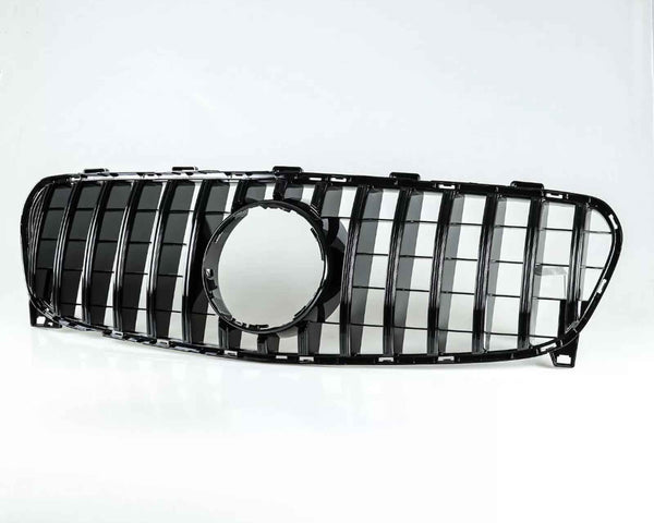 Car grille with vertical black slats and a circular central cutout, resting on a white surface, isolated against a plain white background.
