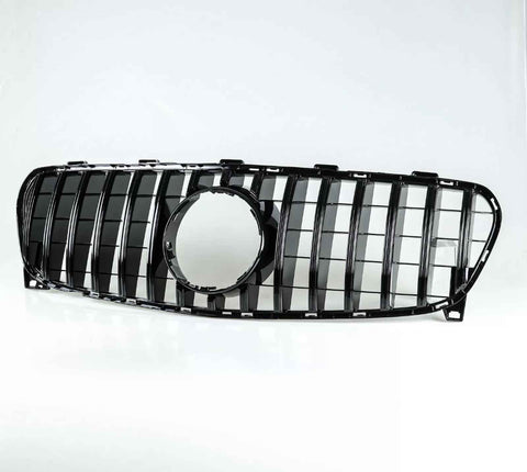 Car grille with vertical black slats and a circular central cutout, resting on a white surface, isolated against a plain white background.