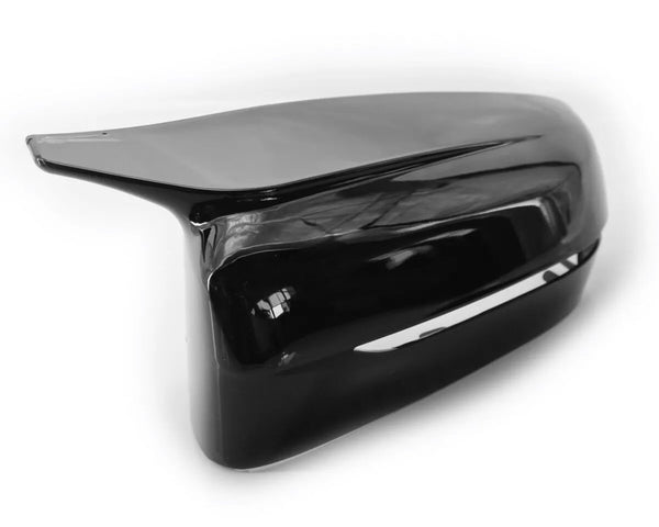 A glossy black car side mirror cover rests on a plain white background, reflecting light and displaying smooth, aerodynamic contours.