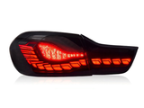 A car taillight, illuminated with bright red LED segments, is shown against a plain white background, highlighting its sleek design and detailing.