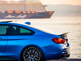 A blue sports car is parked by a waterfront at sunset, with a large cruise ship labeled 