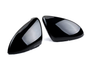 Two shiny black car mirror covers are lying side by side on a plain white background, reflecting light softly across their smooth, contoured surfaces.