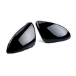 Two shiny black car mirror covers are lying side by side on a plain white background, reflecting light softly across their smooth, contoured surfaces.