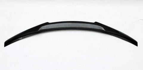Curved black car spoiler rests horizontally on a plain white background, featuring a sleek, aerodynamic design with a central textured section, suggesting structural reinforcement or aesthetic detail.