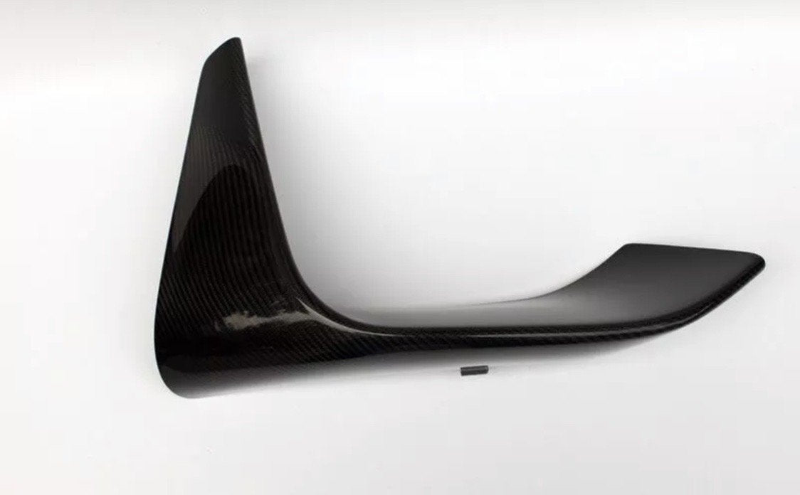 A black carbon fiber car spoiler is angled sideways against a plain white background, displaying its aerodynamic, curved shape and glossy finish.