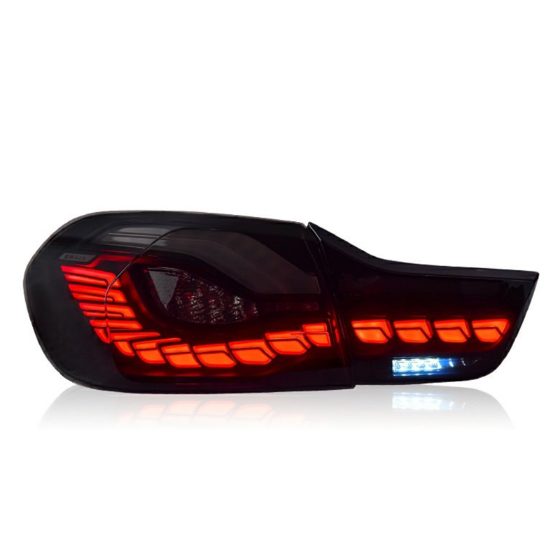 A car taillight is illuminated in bright red and white sections against a white background, showcasing a modern, segmented design with reflective detailing.