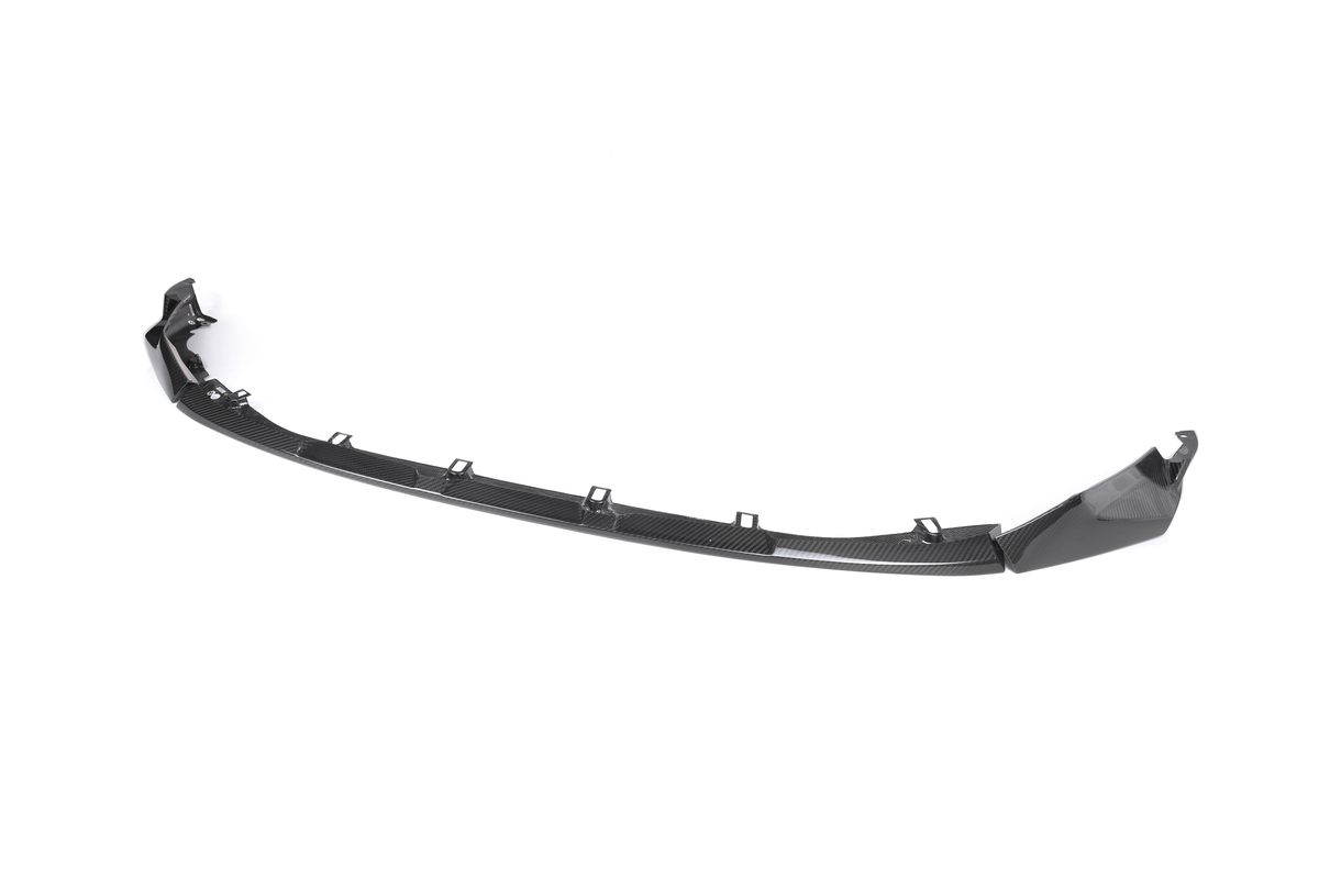 A black car front splitter with a sleek, curved design rests on a plain white background, featuring multiple mounting points along its length.