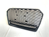 A hexagonal-patterned car grille, featuring a glossy black finish, rests on a white surface. The grille's design includes a prominent honeycomb structure, commonly used for automotive front ends.
