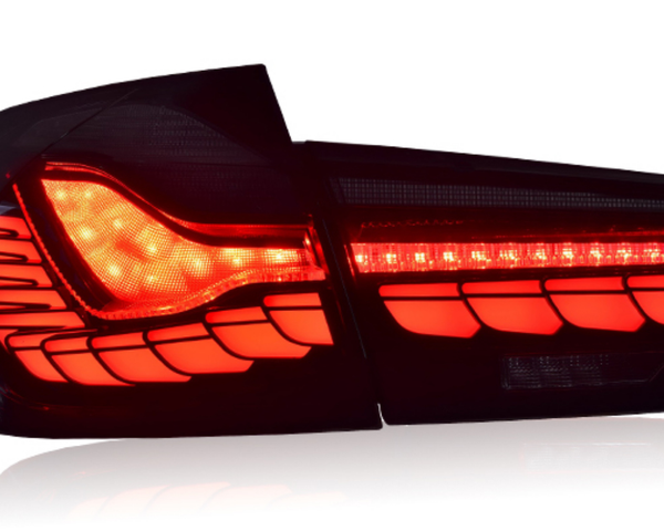 A sleek, modern car taillight, illuminated in bright red with intricate patterns, set against a plain white background.