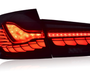 A sleek, modern car taillight, illuminated in bright red with intricate patterns, set against a plain white background.