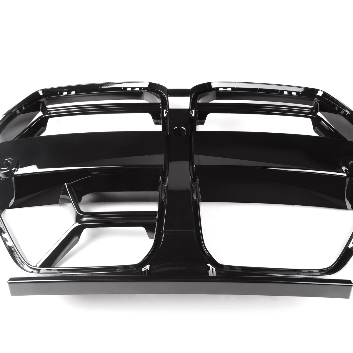 A shiny black car grille, featuring two adjacent rectangular openings, lies on a plain white background. The grille has a glossy, reflective surface with a symmetrical design.