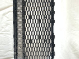 The black, hexagonal-patterned car grille is lying flat, showing its structured grid design on a white fabric backdrop, emphasizing its rectangular shape and multiple attachment clips.