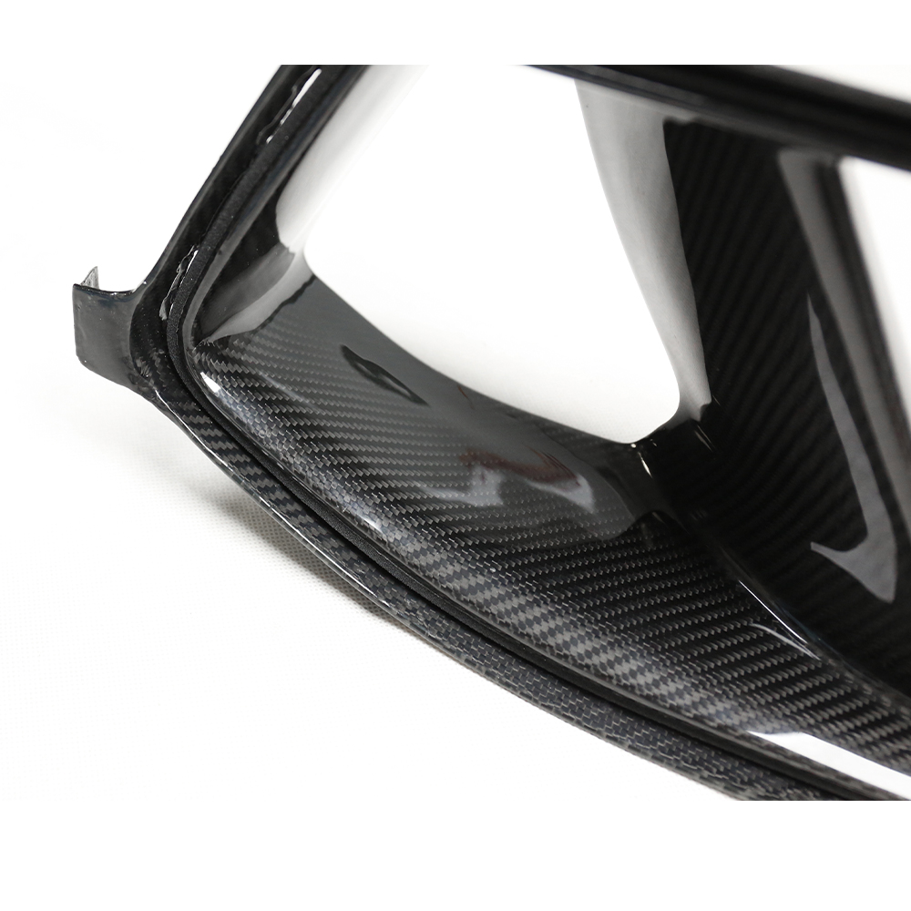 A carbon fiber car part resting on a white surface, displaying a glossy, textured finish with sharp edges and curves.