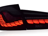 A sleek car taillight is illuminated in bright red, showcasing its angular design, isolated against a plain white background.