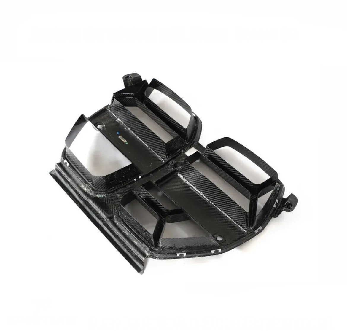 Carbon fiber car grille, angled forward, showing a sleek, black design with angular slats. Positioned on a white background, it appears ready for installation.