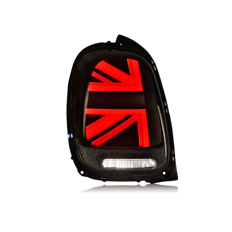 A black car taillight features illuminated red Union Jack design details, with a white horizontal light beneath, highlighting a modern automotive design against a plain background.