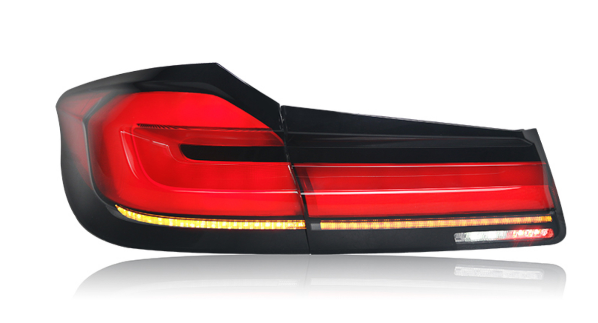 A sleek, modern car taillight with red, black, and amber segments, set against a white background, displaying sharp geometric lines and reflective surfaces.