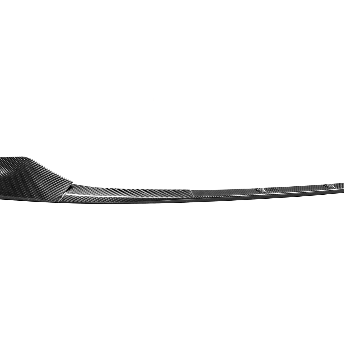 A carbon fiber car splitter is lying horizontally on a white background, displaying its curved, aerodynamic design, and textured pattern.