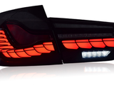 A car taillight glows with vibrant red LED segments, accented by a horizontal strip of white LEDs, set against a dark background, reflecting on a shiny surface.