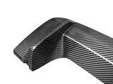 A carbon fiber car part, featuring a sleek, curved design with a glossy finish, lies against a plain white background.