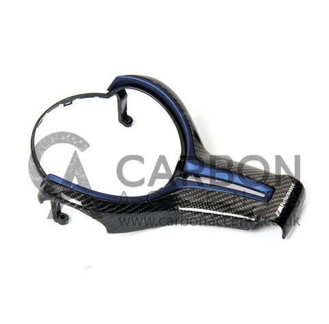 A carbon fiber car steering wheel trim with a blue accent rests on a plain surface. Text reads "M Performance" and a watermark "CARBON ACCENTS www.carbonaccents.co.uk" overlays the image.