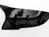 A black, fin-shaped plastic car part with attachment clips sits on a white background. Text on the surface reads: 
