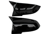 Two black, shiny car mirror covers are displayed against a white background. The top cover shows its inner side with attachment points, while the bottom displays a smooth exterior surface.