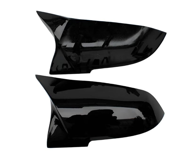 Two black, shiny car mirror covers are displayed against a white background. The top cover shows its inner side with attachment points, while the bottom displays a smooth exterior surface.