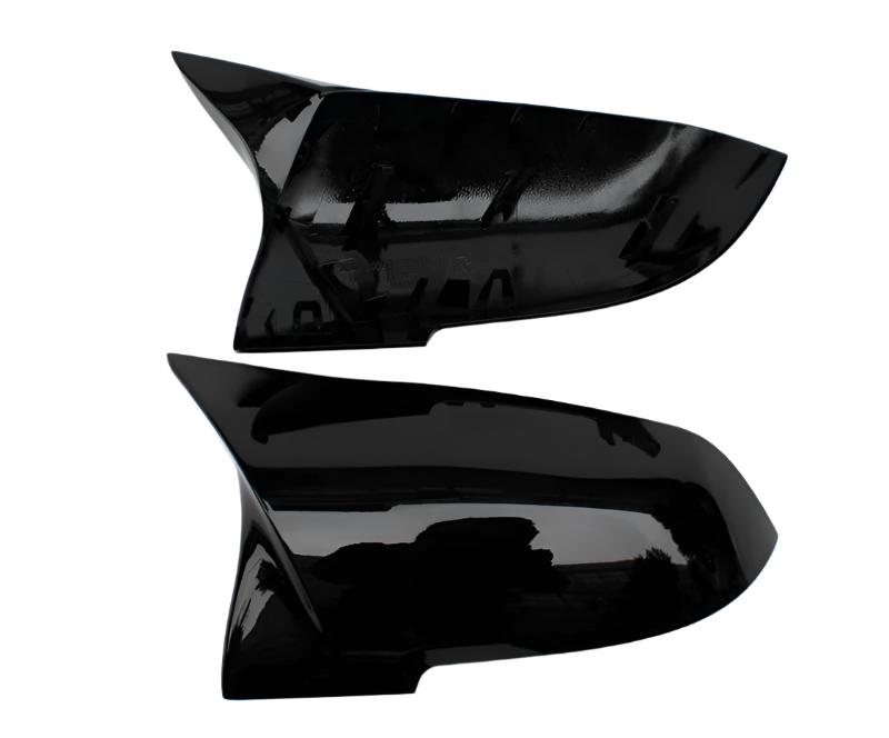 Two sleek black car side mirror covers are displayed horizontally against a plain white background. The covers have a glossy finish and aerodynamic design, suggesting a modern style.