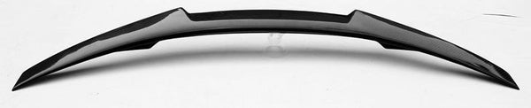 A sleek, curved car spoiler rests on a flat, white surface, showcasing a streamlined design with sharp edges and a glossy finish.
