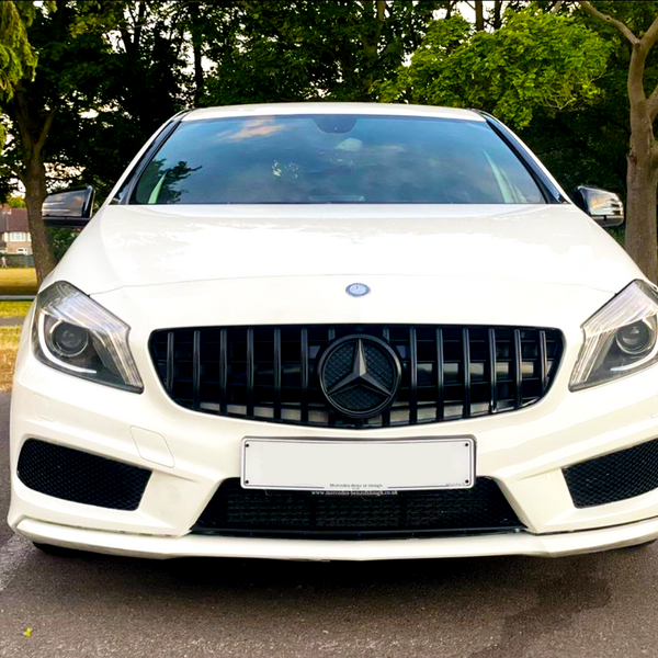 White car with a black grille and circular emblem, parked in an outdoor setting surrounded by lush green trees and a clear sky. License plate text: "Mercedes Benz of Ipswich www.mercedes-benzofipswich.co.uk".