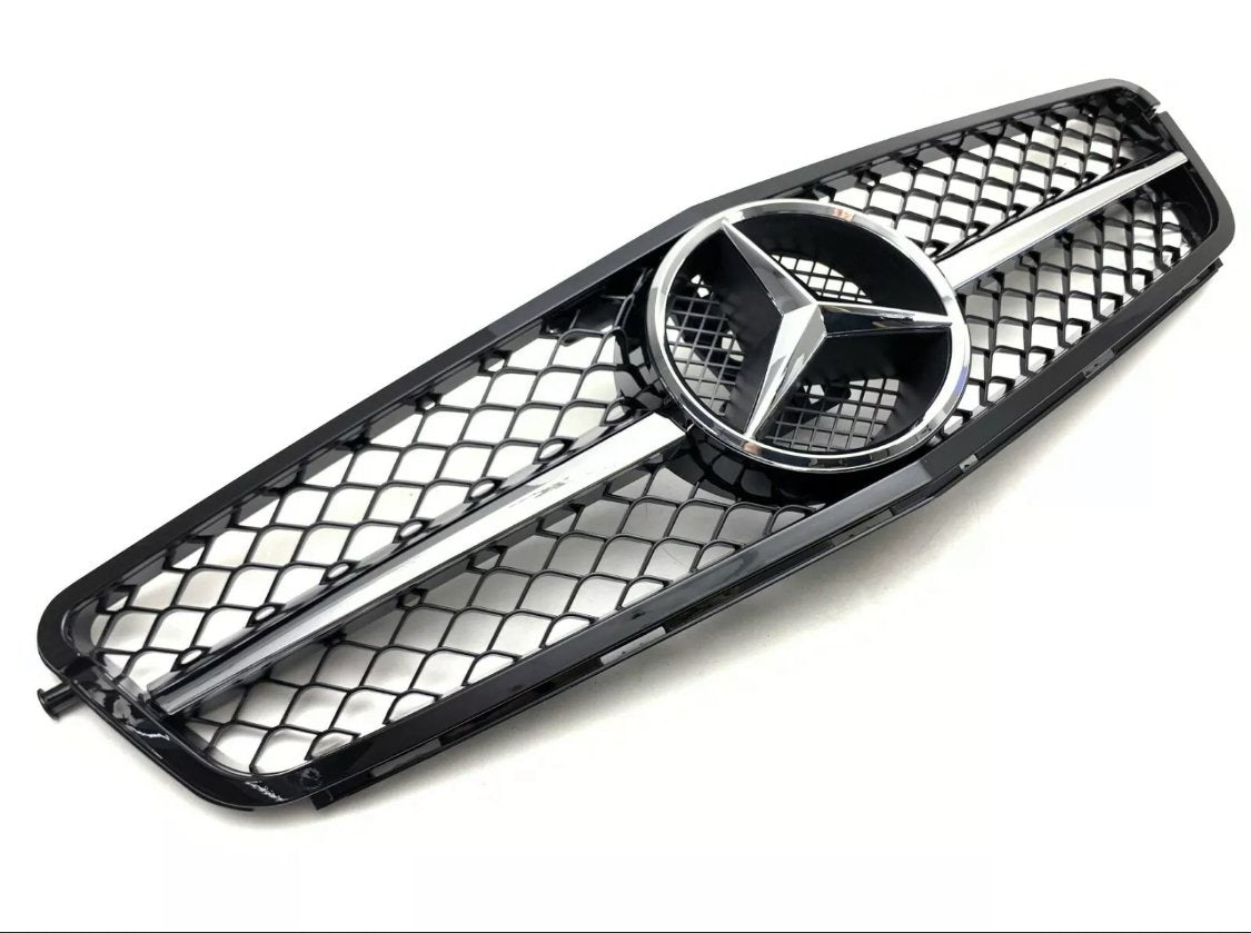 A black car grille features a central silver emblem with three pointed stars, bordered by a mesh pattern against a plain white background.