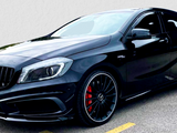 A sleek, black Mercedes-Benz hatchback with sporty, red brake calipers is parked on asphalt. It has a distinctive front grille and the emblem 
