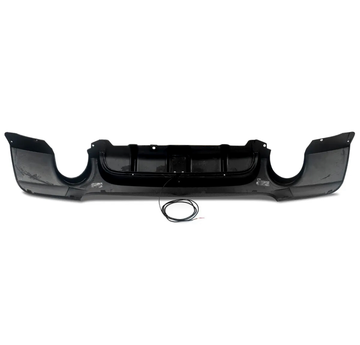 A black car bumper with an aggressive design is shown laying flat on a white background. A coiled wire is placed in front of it, implying potential attachment or installation.