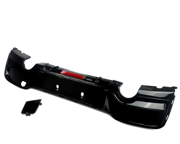 A black car bumper with integrated red reflector lies against a plain white background. A separate smaller black panel is positioned beside it, suggesting assembly components.