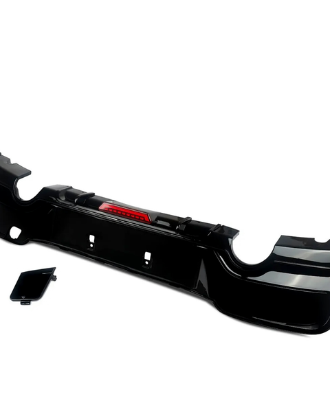 A black car bumper with integrated red reflector lies against a plain white background. A separate smaller black panel is positioned beside it, suggesting assembly components.