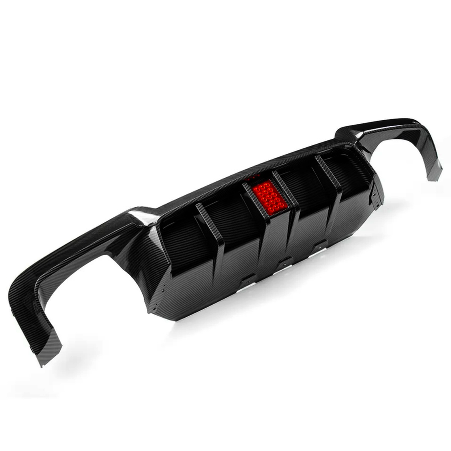 A carbon fiber car diffuser with a central red reflector. It features fins for aerodynamic purposes and is set against a plain white background, highlighting its sleek design.