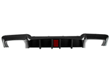 Carbon fiber car rear diffuser with integrated red light sits against a white background, showing aerodynamic fins and contoured edges designed for performance improvement in automotive applications.