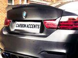 A rear view of a black BMW with notable carbon accents. The license plate reads 