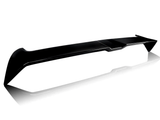 A sleek black car spoiler rests on a reflective white surface, showcasing its aerodynamic design and angled edges.