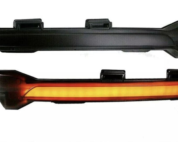 Two black automotive light fixtures are shown. The top fixture is unlit, while the bottom fixture emits a continuous amber glow. Both have mounting brackets and are isolated on a white background.