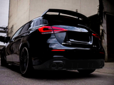 A black Mercedes-Benz AMG A-Class car is parked in an urban alley. It's viewed from the rear, emphasizing the distinctive taillights, spoiler, and dual exhausts. Text: 