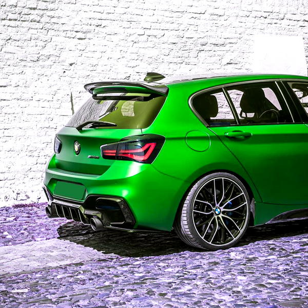 A bright green hatchback car is parked on a cobblestone path, situated against a textured white brick wall.