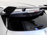 A car's rear section with a prominent black spoiler is parked indoors. The silver vehicle displays a Mercedes-Benz emblem and AMG badge, with a rear wiper and tinted windows.
