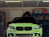 A sleek green car is parked in a cluttered garage, surrounded by shelves filled with boxes and various household items.