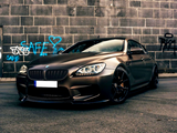A sleek BMW car is parked on an urban street, with blue graffiti reading 