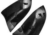 Two black plastic automotive mirror covers are positioned side by side. They are curved and feature attachment hooks and grooves on their inner surfaces, set against a plain white background.