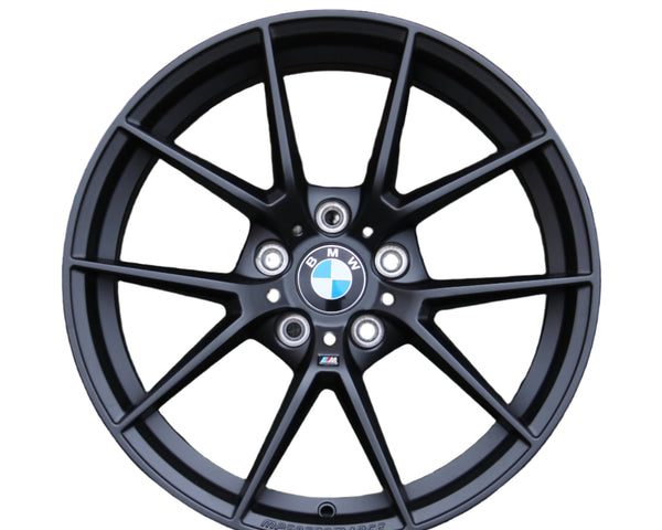 A black BMW alloy wheel features a ten-spoke design with the BMW logo at the center. "M PERFORMANCE" is embossed on the rim, set against a plain white background.