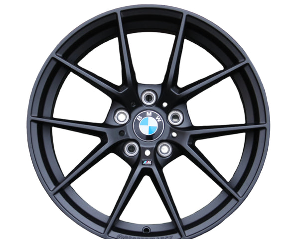 A black alloy wheel with a BMW logo at the center, featuring a multi-spoke design. Text includes "M PERFORMANCE" at the bottom edge and a small "M" badge. Background is white.
